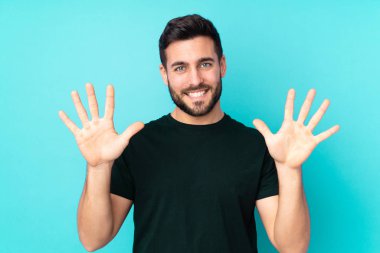 Beyaz tenli yakışıklı adam mavi arka planda izole edilmiş. Parmaklarıyla 10 kişi sayıyor.