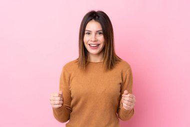 Soyutlanmış pembe arka planda genç bir kadın galibiyeti kutluyor.