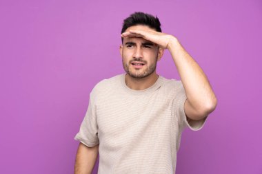 Soyutlanmış mor bir geçmişi olan genç yakışıklı bir adam bir şeye bakmak için uzaklara bakıyor.