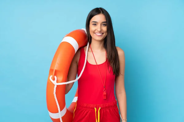 Lifeguard woman over isolated blue background with lifeguard equipment and smiling a lot