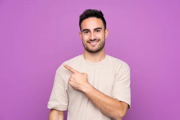 Joven Hombre Guapo Sobre Fondo Púrpura Aislado Apuntando Lado Para — Foto de Stock