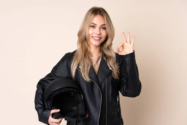 오토바이 헬멧을 러시아 소녀는 베이지 배경에서 손가락으로 오케이 사인을 표시했다 — 스톡 사진