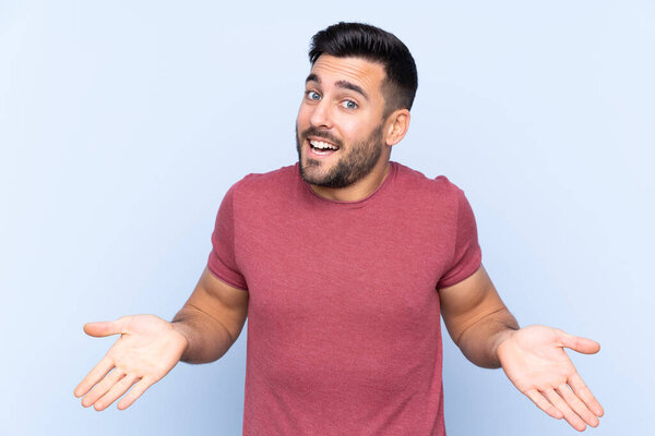 Young handsome man with beard over isolated blue background smiling