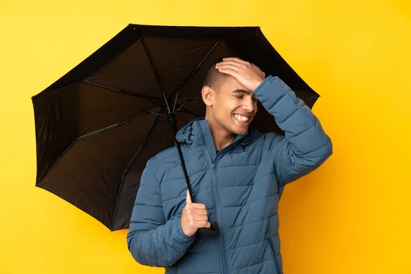 年轻英俊的男子拿着一把雨伞遮挡在孤立的黄色背景下 他意识到了什么 并打算解决这个问题 — 图库照片