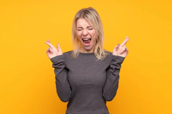 Jonge Blonde Vrouw Geïsoleerde Gele Achtergrond Met Vingers Kruisen — Stockfoto