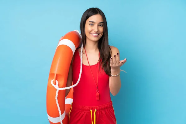 Lifeguard woman over isolated blue background with lifeguard equipment and inviting to come with hand