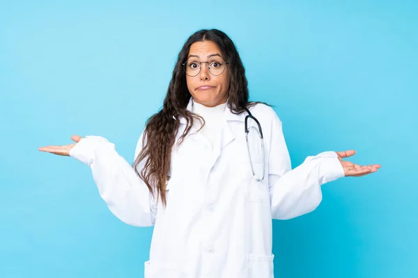 Junge Ärztin Über Isoliertem Blauem Hintergrund Hat Zweifel Mit Verwirrtem — Stockfoto