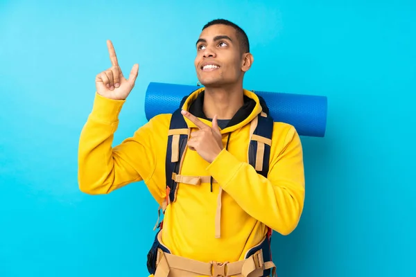 Junger Bergsteiger Mit Großem Rucksack Über Isoliertem Blauem Hintergrund Der — Stockfoto