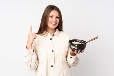 Beyaz arka planda izole edilmiş genç beyaz kız elinde çubuklarla elinde bir kase erişte tutarken harika bir fikir olduğunu gösteriyor.