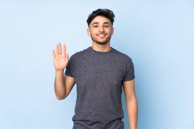 Arap yakışıklı adam izole edilmiş arka planda mutlu bir ifadeyle selamlıyor.