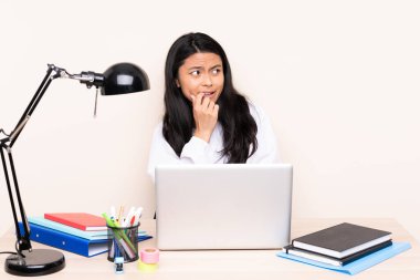 İş yerinde bilgisayarlı Asyalı bir kız bej arka planda izole edilmiş gergin ve korkmuş.