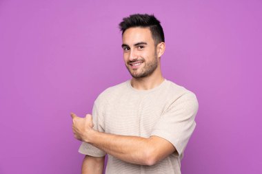 İzole edilmiş mor arka planı olan yakışıklı bir genç.