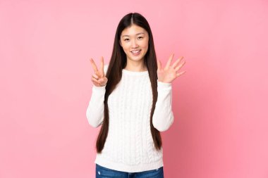 Asyalı genç bir kadın tecrit edilmiş arka planda yediyi parmaklarıyla sayıyor