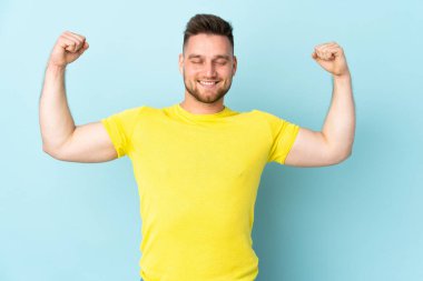 Mavi arka planda izole edilmiş, güçlü bir hareket yapan Rus yakışıklı adam.