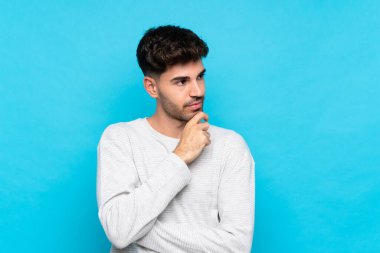 Genç adam soyutlanmış mavi arka plan yan tarafa bakıyor.