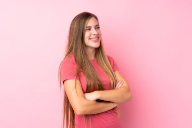 Soyutlanmış pembe arka planda genç sarışın kız yan tarafa bakıyor.