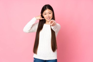 Asyalı genç bir kadın izole edilmiş arka planda telefon hareketi yapıyor ve ön tarafı işaret ediyor.