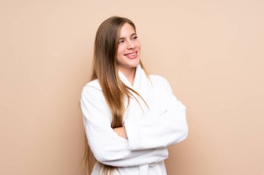 Bornozlu genç bir kız soyutlanmış arka planda yan tarafa bakıyor.