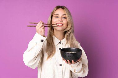 Mor arka planda izole edilmiş genç Rus kız elinde çubuklu bir kase erişte tutuyor.