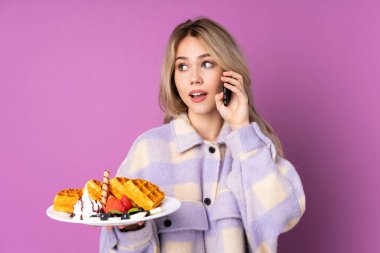 Mor arka planda gözleme tutan genç Rus kız cep telefonuyla sohbet ediyor.