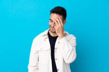 Genç, yakışıklı, soyutlanmış, mavi arka plan gülüyor.