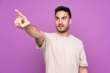İzole edilmiş mor arka planı olan yakışıklı bir genç.