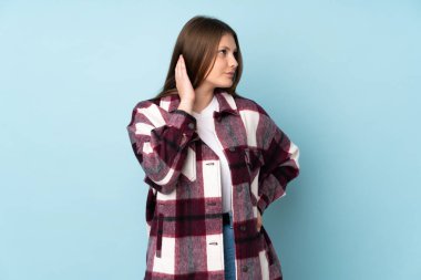 Kafkasyalı genç bir kız mavi arka planda izole edilmiş bir fikir düşünüyor.