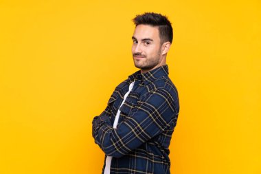 Genç yakışıklı adam, izole edilmiş sarı arka plan gülüyor.