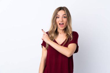 İzole edilmiş beyaz arka planı olan genç bir kadın şaşırmış ve işaret ediyor.