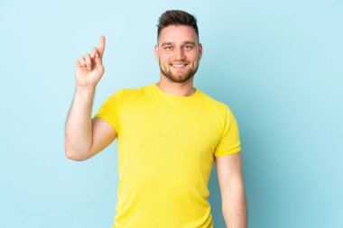 Mavi arka planda izole edilmiş Rus yakışıklı adam harika bir fikre işaret ediyor.