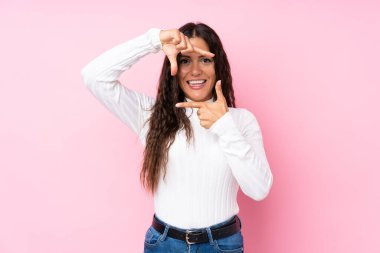 Soyutlanmış pembe arka planda odaklanan genç bir kadın. Çerçeve sembolü