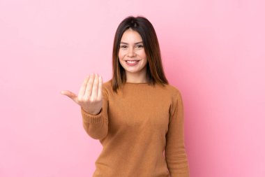 Soyutlanmış pembe arka planı olan genç bir kadın, bizimle gelmesi için davet ediyor. Gelmene sevindim.