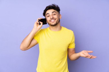 Arbiyalı yakışıklı adam izole edilmiş arka planda biriyle cep telefonuyla sohbet ediyor.