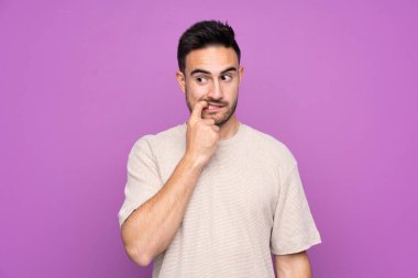 Genç, yakışıklı, soyutlanmış, mor arka planı gergin ve korkmuş bir adam.