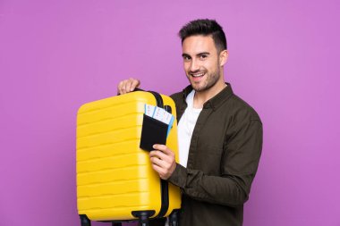 İzole edilmiş mor bir geçmişi olan genç yakışıklı bir adam. Tatilde bavul ve pasaportla.