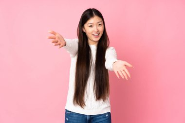 Asyalı genç bir kadın soyutlanmış arka planda sunuyor ve davet ediyor.