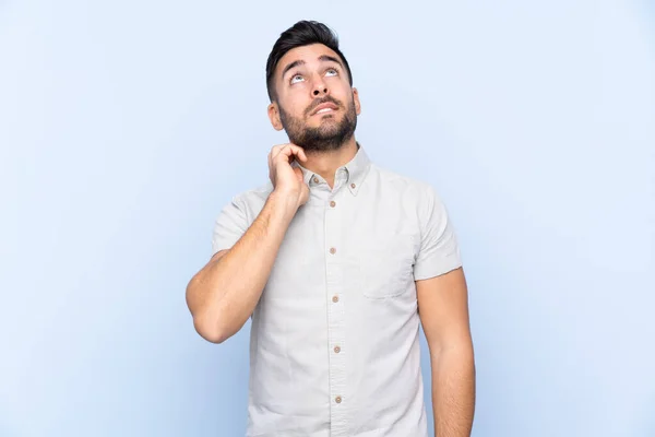 Jovem Homem Bonito Com Barba Sobre Fundo Azul Isolado Pensando — Fotografia de Stock