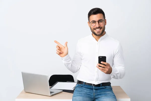 Jovem Empresário Segurando Telefone Celular Apontando Dedo Para Lado — Fotografia de Stock