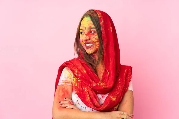 若いですインド人女性とともにカラフルなホリパウダーオン彼女の顔絶縁上のピンクの背景探している側 — ストック写真