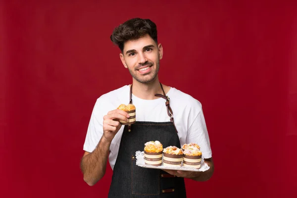 Junger Mann Über Isoliertem Hintergrund Mit Mini Kuchen — Stockfoto