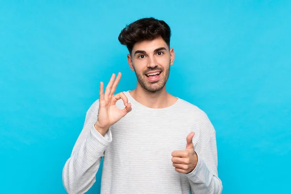 Ung Man Över Isolerad Blå Bakgrund Visar Tecken Och Tumme — Stockfoto