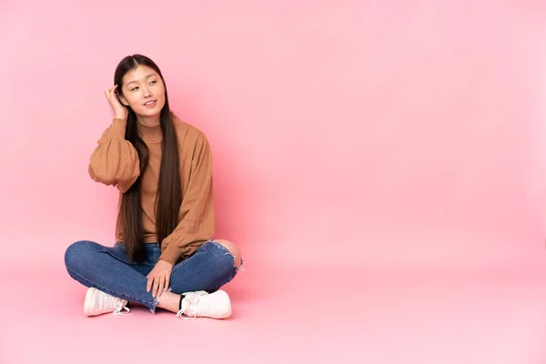 Junge Asiatische Frau Sitzt Auf Dem Boden Isoliert Auf Rosa — Stockfoto