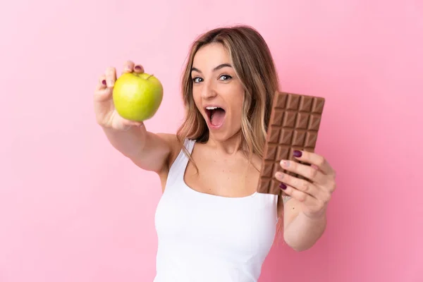 Young Woman Isolated Pink Background Taking Chocolate Tablet One Hand — Stock Photo, Image