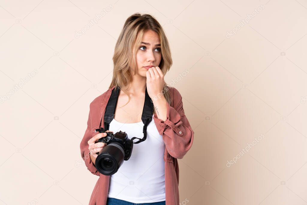 Young photographer girl over isolated background nervous and scared putting hands to mouth