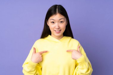 Mor arka planda yalıtılmış Asyalı genç bir kadın. Sürpriz bir yüz ifadesi var.