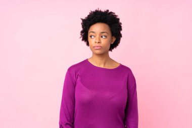 Afro-Amerikalı kadın pembe arka planda şüpheli hareketler yapıyor.