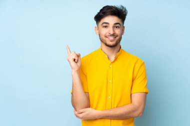 Münzevi geçmişi olan yakışıklı Arap bir adam mutlu ve yukarıya bakıyor.