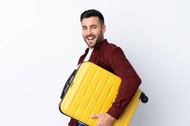 Genç yakışıklı adam izole edilmiş beyaz arka planda seyahat valiziyle tatilde.