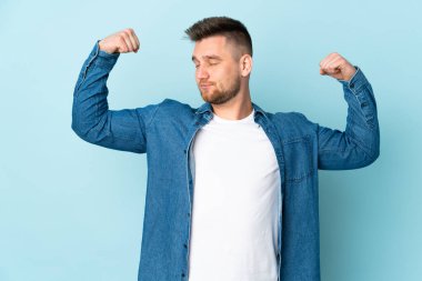 Mavi arka planda izole edilmiş, güçlü bir hareket yapan Rus yakışıklı adam.