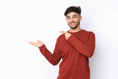İzole edilmiş arka plan üzerinde yakışıklı Arap bir adam bir reklam eklemek için avucunun içinde hayali bir metin tutuyor.